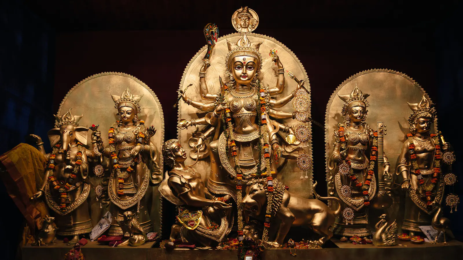 Gilded festival images of Durga on her lion flanked by Lakshmi, Saraswati, Ganesha and Kartikeya inside a pandal