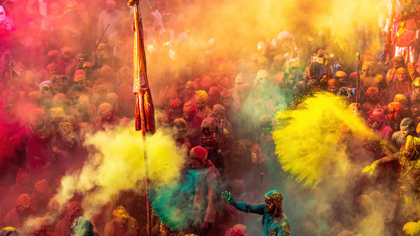 Clouds of yellow and pink colour thrown over a crowd at Lathmar Holi in Nandgaon