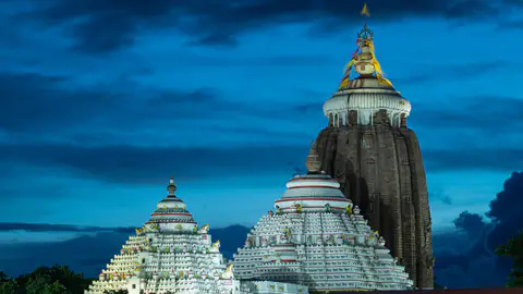 The white towers of the Jagannath Temple at Puri lit against a deep blue evening sky