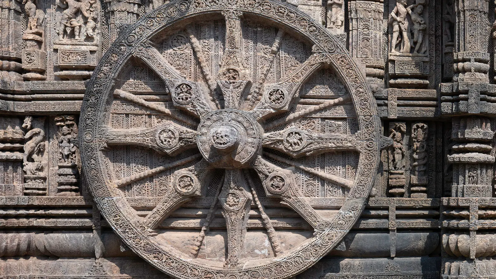 A carved stone chariot wheel with eight spokes on the wall of the Konark Sun Temple