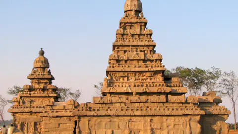 The stepped stone towers of the Shore Temple in warm evening light against a clear sky